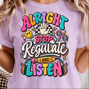 May include: A light purple t-shirt featuring a colorful graphic with the text ALRIGHT STOP REGULATE AND LISTEN. The design includes a hand, a smiley face, checkered sunglasses, a yellow pencil, and headphones in vibrant shades of pink, blue, and yellow.