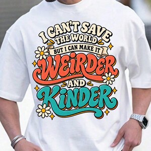 May include: A white t-shirt featuring a colorful graphic print with the text I CAN'T SAVE THE WORLD BUT I CAN MAKE IT WEIRDER AND KINDER. The design includes orange and teal lettering, yellow star accents, and white daisy flowers.