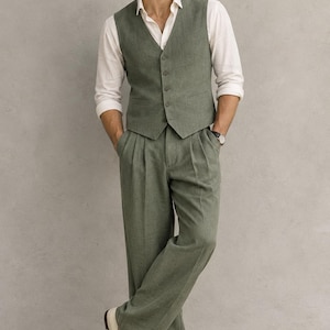 May include: A sage green waistcoat and matching pleated trousers worn with a white long-sleeved button-down shirt and cream-coloured loafers. The waistcoat features a five-button closure and two front pockets, while the trousers have a wide-leg cut.