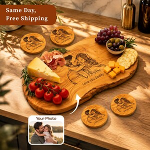 May include: A wooden serving board with a live edge featuring a laser-engraved illustration of a person hugging a child and the text Love you Daddy. Four matching round wooden coasters with the same engraving are included with the board.