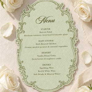 May include: A pale green die-cut menu card with an ornate dark green border. The text reads: Menu, STARTER Burrata Salad, MAIN COURSE Herb-Roasted Chicken, DESSERT Vanilla Panna Cotta, DRINKS Sparkling Wine, Red & White Wine, Soft Drinks & Mineral Water.