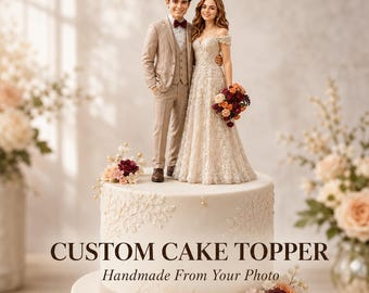 May include: A custom cake topper featuring a miniature couple in wedding attire standing on a white tiered cake. The text CUSTOM CAKE TOPPER Handmade From Your Photo is printed on the cake. The figures wear a tan suit and lace gown.