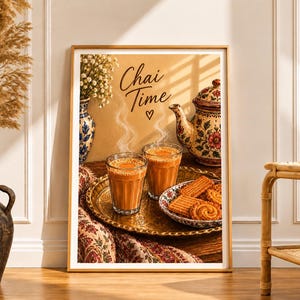 Op de afbeelding: Een ingelijste kunstprint met een warmgekleurde illustratie van twee glazen dampende chai-thee, een theepot met bloemmotieven en een bordje met koekjes op een koperen dienblad. De tekst Chai Time met een klein hartje staat in het midden bovenaan.