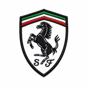 May include: A shield-shaped embroidered patch featuring a white background with a black prancing horse silhouette in the center. The letters S and F are stitched in black below the horse. The top border displays green, white, and red stripes.