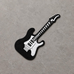 May include: An embroidered patch in the shape of an electric guitar. The body and headstock are black with white thread detailing outlining the fretboard, strings, and pickguard. The design features a solid black base with white stitching.