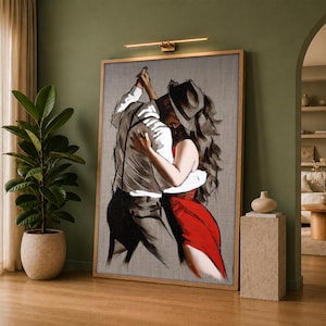 May include: A framed vertical wall art print depicting a stylised illustration of two figures dancing. One figure wears a hat, a white shirt, and dark trousers, while the other figure wears a vibrant red dress. The artwork features bold black outlines.