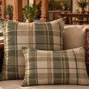 May include: Two square and rectangular throw pillows featuring a plaid pattern in shades of sage green, cream, and thin gold metallic threads. The fabric has a visible quilted texture with horizontal and vertical stitching across the surface.