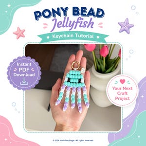 Könnte beinhalten: Ein Quallen-Schlüsselanhänger aus hellblauen, weißen und violetten Pony-Perlen mit schwarzen Perlenaugen, einem goldfarbenen Metallring und einem kleinen Muschel-Anhänger. Die Grafik enthält den Text PONY BEAD Jellyfish Keychain Tutorial, Instant PDF Download und Your Next Craft Project.