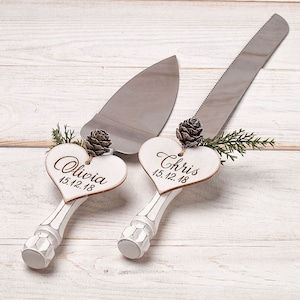 May include: White wedding cake server set with wooden heart-shaped handles. The handles are decorated with the names "Olivia" and "Chris" and the date "15.12.18".