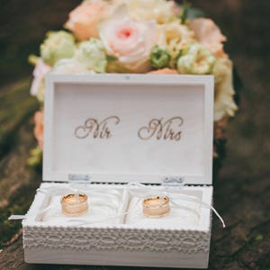 Pu&ograve; includere: Scatola di legno bianca con bordo in pizzo, incisa con "Mr. & Mrs." e contenente due fedi nuziali d'oro.