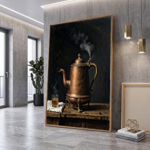 Könnte beinhalten: Ein gerahmter Wandkunstdruck, der eine kupferne Kaffeekanne auf einer Holzoberfläche zeigt, aus deren Ausguss Dampf aufsteigt. Neben der Kanne steht ein kleines Glas mit einer goldenen Flüssigkeit auf einem weißen Tuch vor einem dunklen Hintergrund.