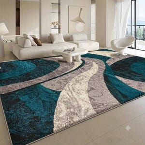 May include: A rectangular area rug featuring a high-pile texture with a bold pattern of swirling, interconnected waves in deep teal, charcoal grey, and cream white. The design consists of large, sweeping curves that span the entire surface.