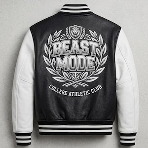 以下が含まれることがあります： ライオンのエンブレム、月桂樹の葉、そして「BEAST MODE COLLEGE ATHLETIC CLUB」の文字が背面に大きくプリントされた、黒と白のバーシティジャケット。白い袖、黒いボディ、黒と白のストライプ柄のリブトリムが特徴です。
