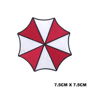 May include: A circular embroidered patch featuring a red and white segmented umbrella design with a black border. The patch measures 7.5cm by 7.5cm, as indicated by the text 7.5cm x 7.5cm printed in the bottom right corner of the image.