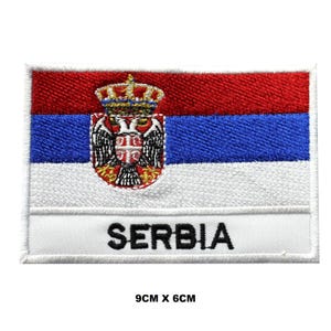 May include: A rectangular embroidered patch featuring the Serbian flag with horizontal red, blue, and white stripes. A gold and red coat of arms with a double-headed eagle is centered on the left. The word SERBIA is stitched in black at the bottom. 9cm x 6cm.