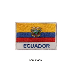 May include: A rectangular embroidered patch featuring the flag of Ecuador with horizontal yellow, blue, and red stripes and a central coat of arms. Below the flag, a white bar displays the text ECUADOR in blue. The patch measures 9cm by 6cm.