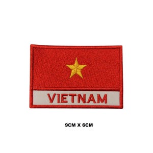 Op de afbeelding: Een rechthoekige geborduurde patch met een rode achtergrond, een gecentreerde gele vijfpuntige ster boven een witte horizontale streep met de rode tekst VIETNAM. De patch meet 9 cm x 6 cm zoals aangegeven in de tekst op de afbeelding.