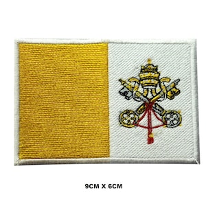 May include: A rectangular embroidered patch featuring the flag of Vatican City with a vertical yellow band on the left and a white band on the right, displaying the crossed keys and papal tiara emblem. The patch measures 9cm x 6cm.