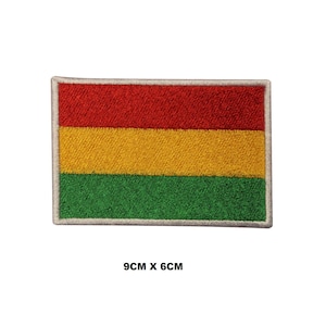 May include: A rectangular embroidered patch featuring three horizontal stripes in red, yellow, and green with a light gray border. The patch displays the text 9CM X 6CM below the design, indicating its physical dimensions of 9 centimeters by 6 centimeters.