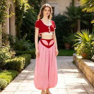 Puede incluir: Un conjunto de dos piezas que consiste en una chaqueta roja corta de manga corta con ribete blanco sobre una capa blanca, combinado con pantalones tipo harén rosas de talle alto con un detalle de cintura roja en forma de V.