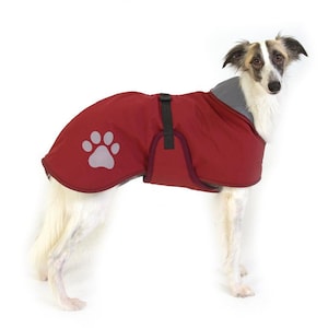 May include: A red dog coat with a gray paw print on the left side. The coat has a black adjustable strap and is made of a water-resistant material.