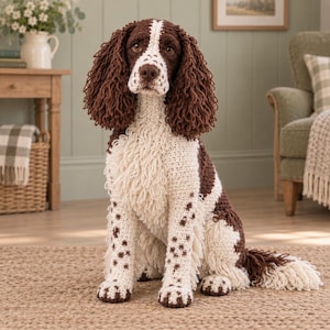 Peut inclure: Une figurine de chien crochetée à la main représentant un épagneul springer. Le chien présente un poitrail et des pattes blancs avec des taches brunes, de longues oreilles brunes bouclées et un visage brun et blanc. La texture crée un pelage.
