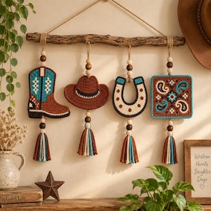May include: A wall hanging featuring a natural wooden branch suspending four crocheted ornaments: a cowboy boot, a hat, a horseshoe, and a square paisley patch. Each piece is accented with wooden beads and a multi-colored yarn tassel.