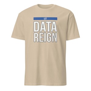 Puede incluir: Una camiseta beige de manga corta con una barra horizontal azul sobre el texto blanco "LET DATA REIGN" impreso en una fuente sans-serif en negrita. La camiseta tiene cuello redondo y un corte estándar con un diseño gráfico sencillo.