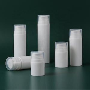 May include: A collection of six white cylindrical cosmetic pump bottles of varying heights. Each bottle features a smooth opaque white body and a clear plastic cap covering the pump mechanism. The bottles are arranged in a group on a dark surface.