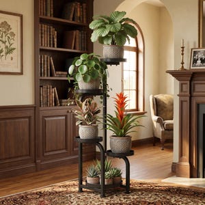 May include: A black metal multi-tiered plant stand featuring five circular shelves holding various potted plants. The pots are grey with a textured leaf pattern. The plants include a large green leafy plant, a round-leaf plant, a bromeliad, and succulents.