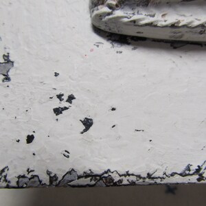 May include: White painted wooden surface with black paint chips and a distressed look.