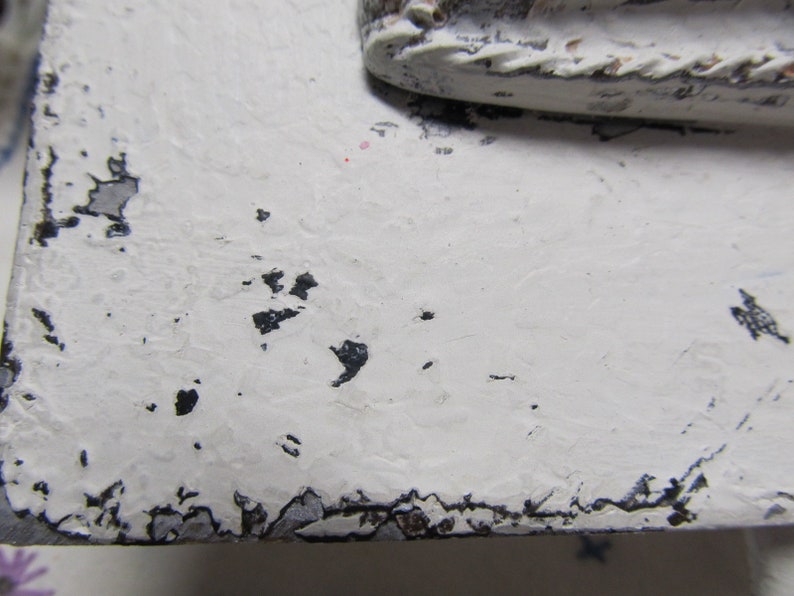 May include: White painted wooden surface with black paint chips and a distressed look.