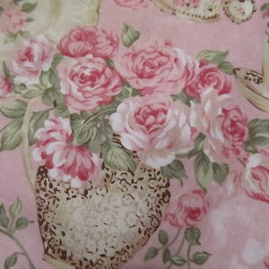 Pu&ograve; includere: Un tessuto floreale in stile vintage con un bouquet di rose rosa in un vaso marrone e bianco. Il tessuto ha uno sfondo rosa ed &egrave; perfetto per progetti di artigianato.