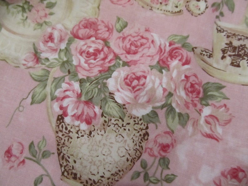 Pu&ograve; includere: Un tessuto floreale in stile vintage con un bouquet di rose rosa in un vaso marrone e bianco. Il tessuto ha uno sfondo rosa ed &egrave; perfetto per progetti di artigianato.