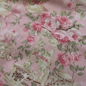 Pu&ograve; includere: Tessuto rosa con un motivo ripetitivo di tazze da t&egrave;, piattini e rose. Il tessuto ha un'estetica vintage e presenta la parola "Roses" stampata su un'ampolla.