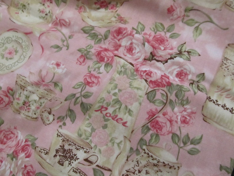 Pu&ograve; includere: Tessuto rosa con un motivo ripetitivo di tazze da t&egrave;, piattini e rose. Il tessuto ha un'estetica vintage e presenta la parola "Roses" stampata su un'ampolla.