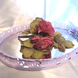 Pu&ograve; includere: Un vassoio ovale di colore lavanda con un bordo decorativo a pizzo. Il vassoio ha una superficie a specchio ed &egrave; decorato con un bouquet di rose rosa.