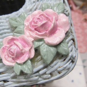 May include: A light blue wicker tissue box cover with two pink roses and green leaves.