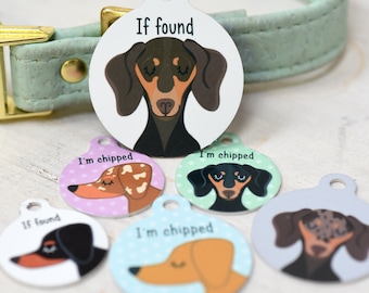 May include: A collection of colorful pet ID tags featuring dachshund illustrations. The tags have a circular shape with a hole at the top for attachment. Some tags read "If found" and "I'm chipped". The tags are in various colors, including white, pink, and blue.