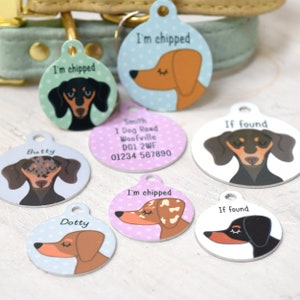 May include: A collection of round pet tags with dachshund illustrations. Some tags say "I'm chipped" and "If found". Other tags have names like "Butty" and "Dotty". The tags are in various colors, including blue, pink, and white.