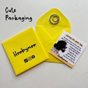 May include: Bright yellow packaging with the text "Cute Packaging" and the brand name "Hoobynoo". Includes a small card with care instructions and a picture of a dog. A silver ring is also included.