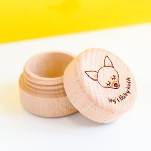 May include: A small wooden box with a lid, the lid has a cartoon fox face with closed eyes and the text "Ivy's Baby Teeth" engraved on it.