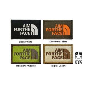Puede incluir: Cuatro parches rectangulares bordados con el texto AIM FOR THE FACE y un gráfico de línea curva. Los parches vienen en combinaciones de negro con blanco, verde oliva con naranja brillante, verde musgo con coyote y un esquema de color desierto digital.