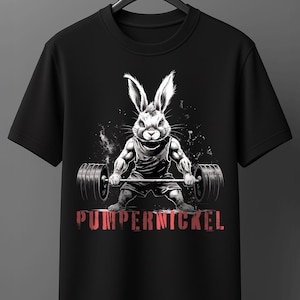 Könnte beinhalten: Ein schwarzes T-Shirt mit kurzen Ärmeln und einer Grafik eines muskulösen Hasen, der eine Langhantel hebt. Der Hase ist in einem weiß-grauen Skizzenstil dargestellt. Unter dem Hasen steht das Wort PUMPERNICKEL in roter Schrift.