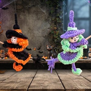 Könnte beinhalten: Zwei gehäkelte Hexen-Ornamente, die in der Luft hängen. Eine Hexe trägt ein schwarz-oranges Kleid mit passendem Hut, während die andere ein lila-hellgrünes Kleid mit passendem Hut trägt. Beide Figuren halten einen kleinen hölzernen Hexenbesen.