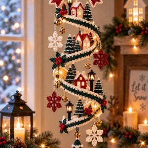 May include: A spiral hanging decoration featuring crocheted elements including a large red and white bow, miniature houses with red roofs, green pine trees, white snowflakes, and red berries. The structure is accented with small gold bells and black street lamps.