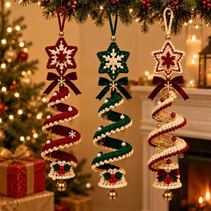 Può includere: Tre ornamenti pendenti all'uncinetto in rosso, verde e crema. Ognuno presenta una stella in cima, un corpo a spirale decorato con piccole perle e fiocchi di neve dorati, un fiocco di velluto e una campanella con bacche rosse alla base.