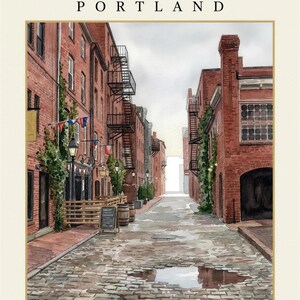 May include: A watercolor print titled WHARF STREET PORTLAND The city collection, depicting a cobblestone street lined with red brick buildings, black metal fire escapes, green climbing vines, street lamps, and a small menu board.