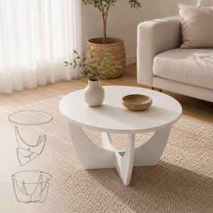 Puede incluir: Una mesa de centro redonda de color blanco con una superficie lisa y una base compuesta por dos paneles curvos entrelazados. Un diagrama de líneas a la izquierda ilustra el montaje del tablero circular sobre los soportes de la base.