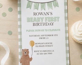 May include: A rectangular birthday invitation card with a sage green gingham border. The text reads: ROWAN'S BEARY FIRST BIRTHDAY, PLEASE JOIN US TO CELEBRATE, SATURDAY, SEPTEMBER 5TH FROM 1-3, ROWAN'S HOUSE 123 MAIN STREET, RSVP TO MICHELLE AT 123-456-7890.